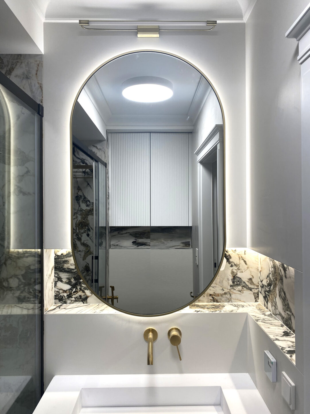 lustro owalne w złotej ramie w łazience nad umywalką