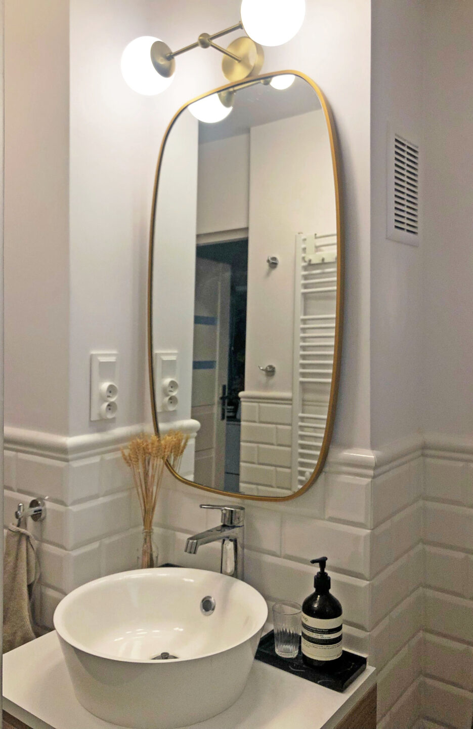 lustro w kształcie beczki w białej łazience nad umywalką