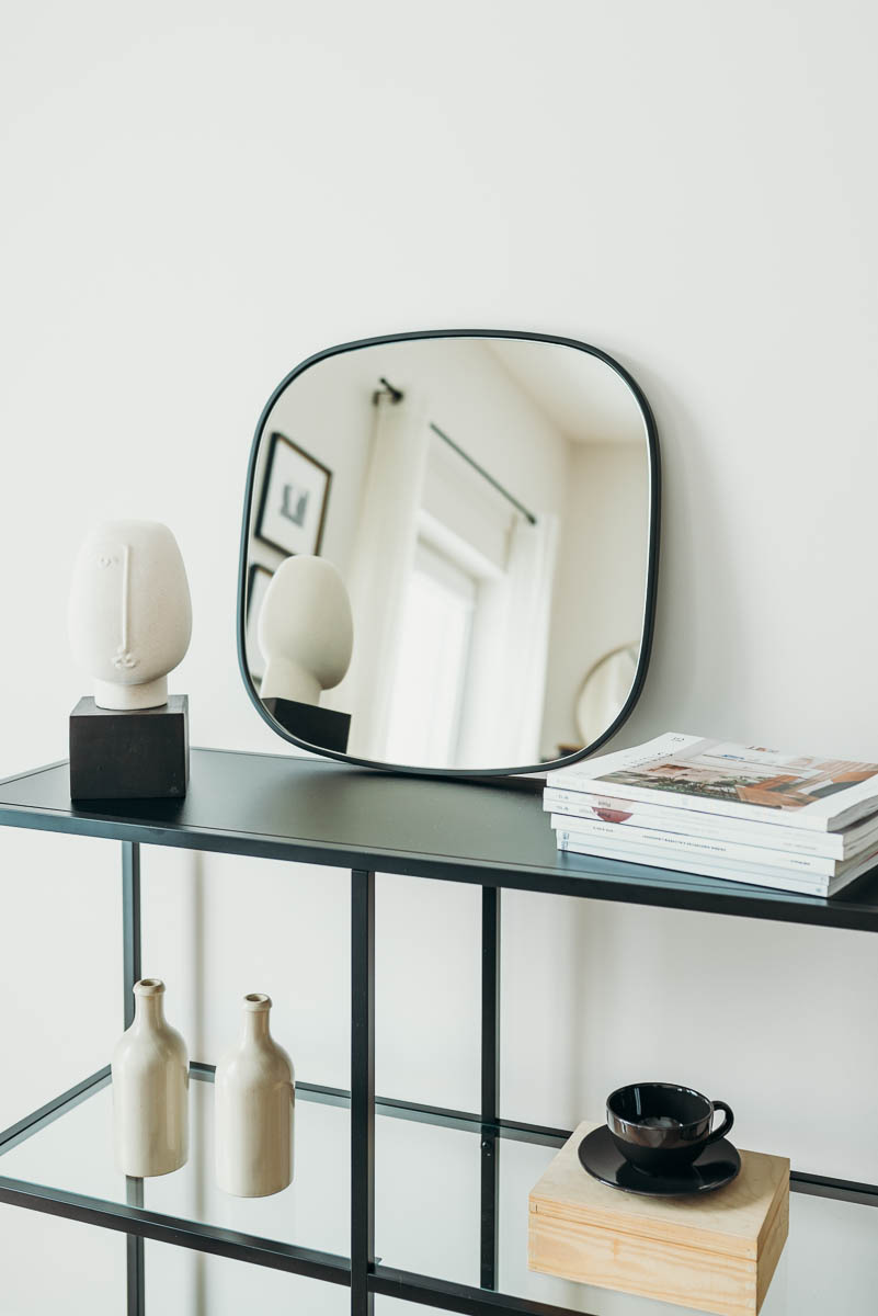 lustro-rubin-w-czarnej-ramie-na-czarnej-konsoli-oparte-o-sciane