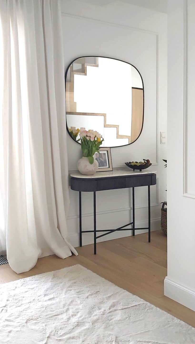 lustro rubin w czarnej ramie nad konsola na jasnej scianie