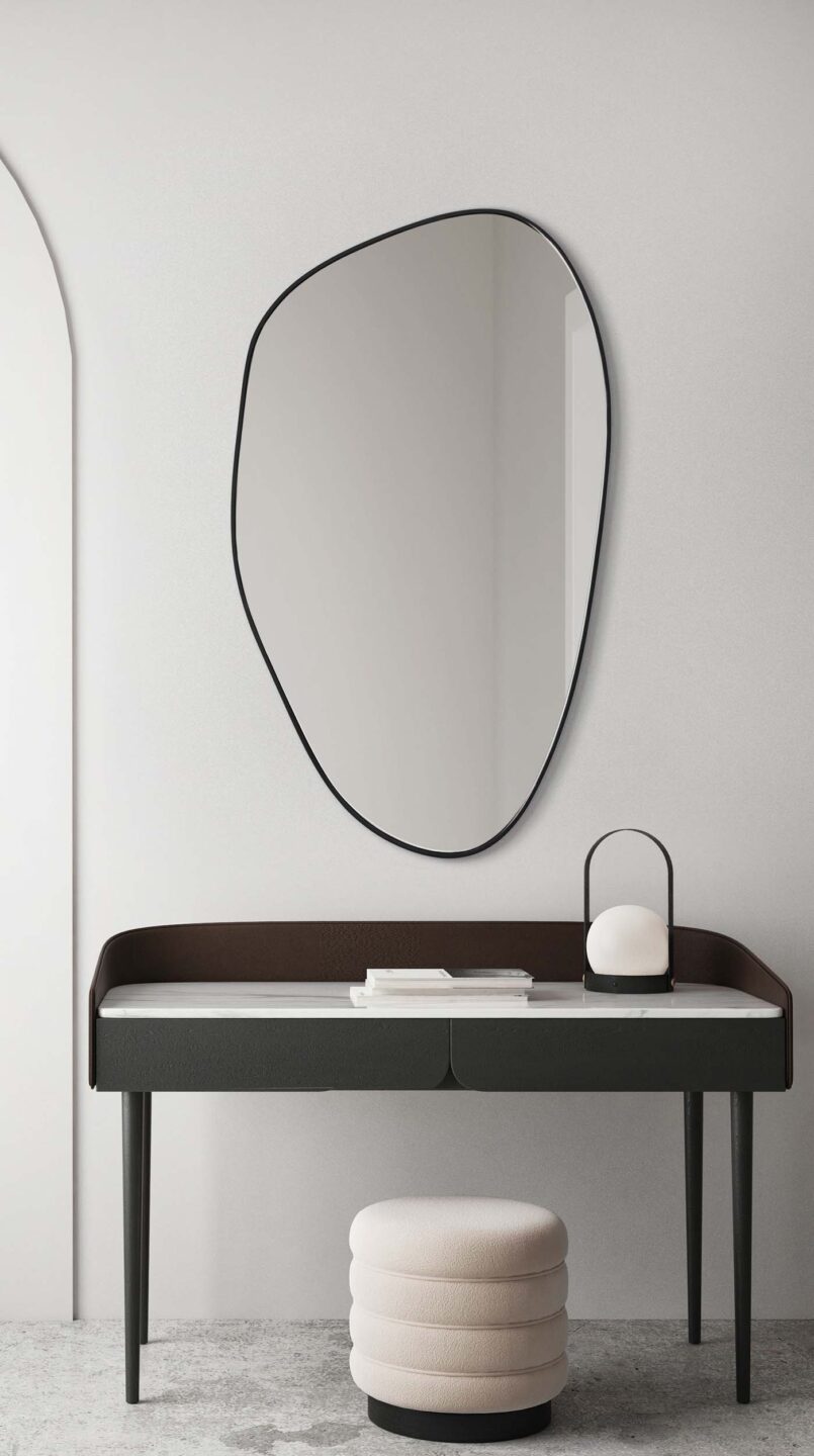 lustro o organicznym kształcie w czarnej ramie nad biurkiem