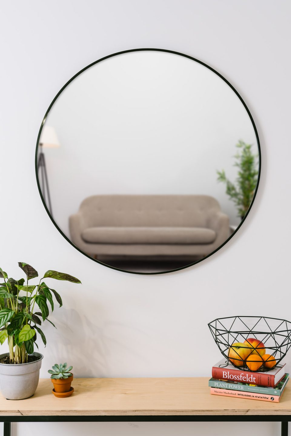 okragle-lustro-w-czarnej-waskiej-ramie-w-salonie-nad-konsola