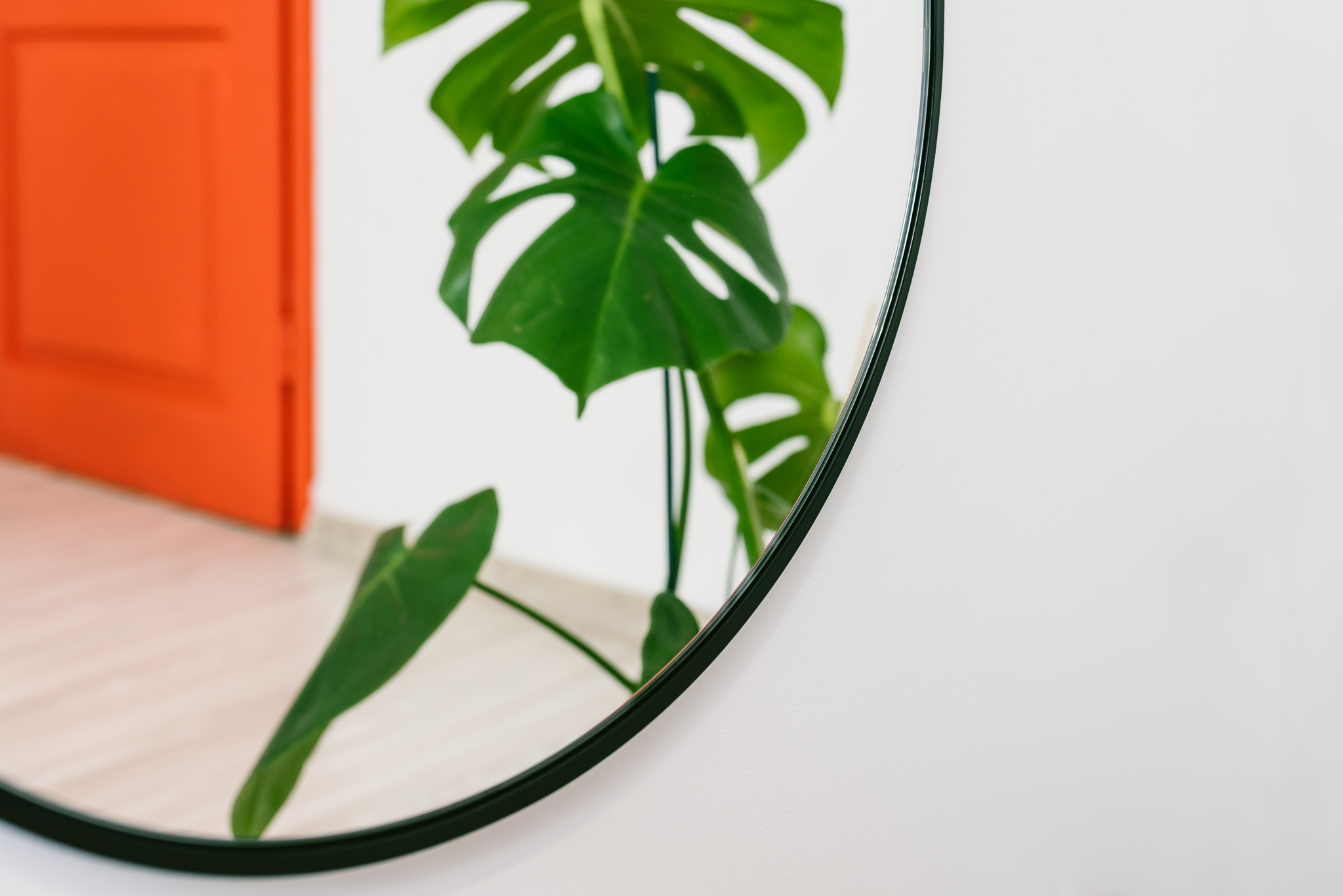 zbliżenie na owalne lustro w czarnej cienkiej ramie w przedpokoju