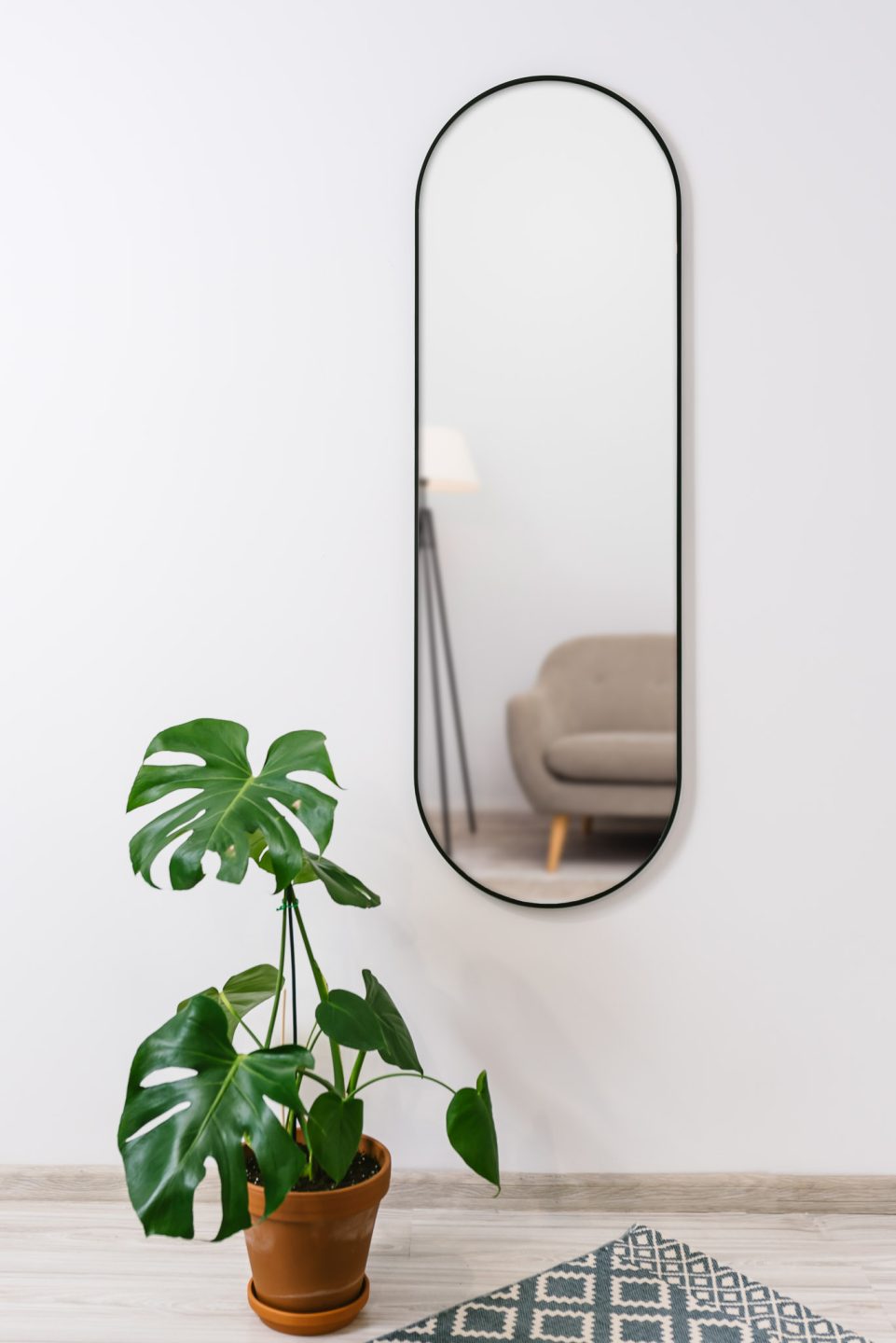 duże owalne lustro na korytarzu wiszące na białej ścianie