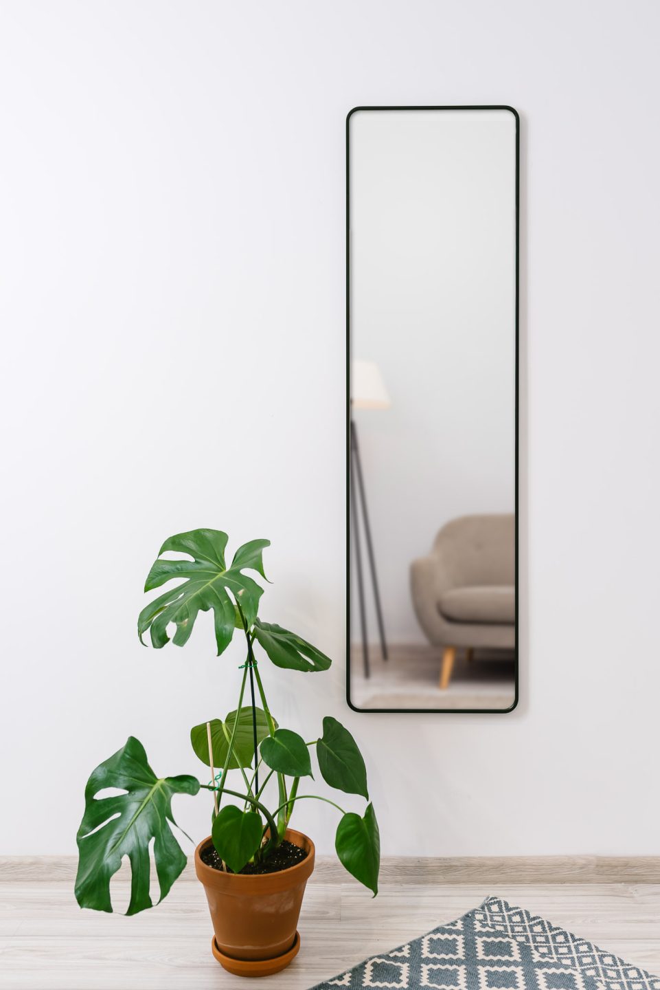 LUSTRO W CZARNEJ RAMIE Z ZAOKRĄGLONYMI NAROŻNIKAMI WISZĄCE W PRZEDPOKOJU