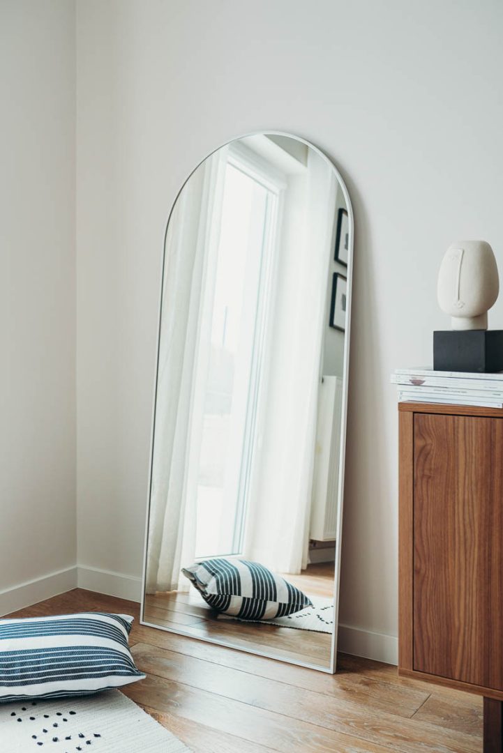 Lustro z łukiem w białej ramie ustawione w korytarzu