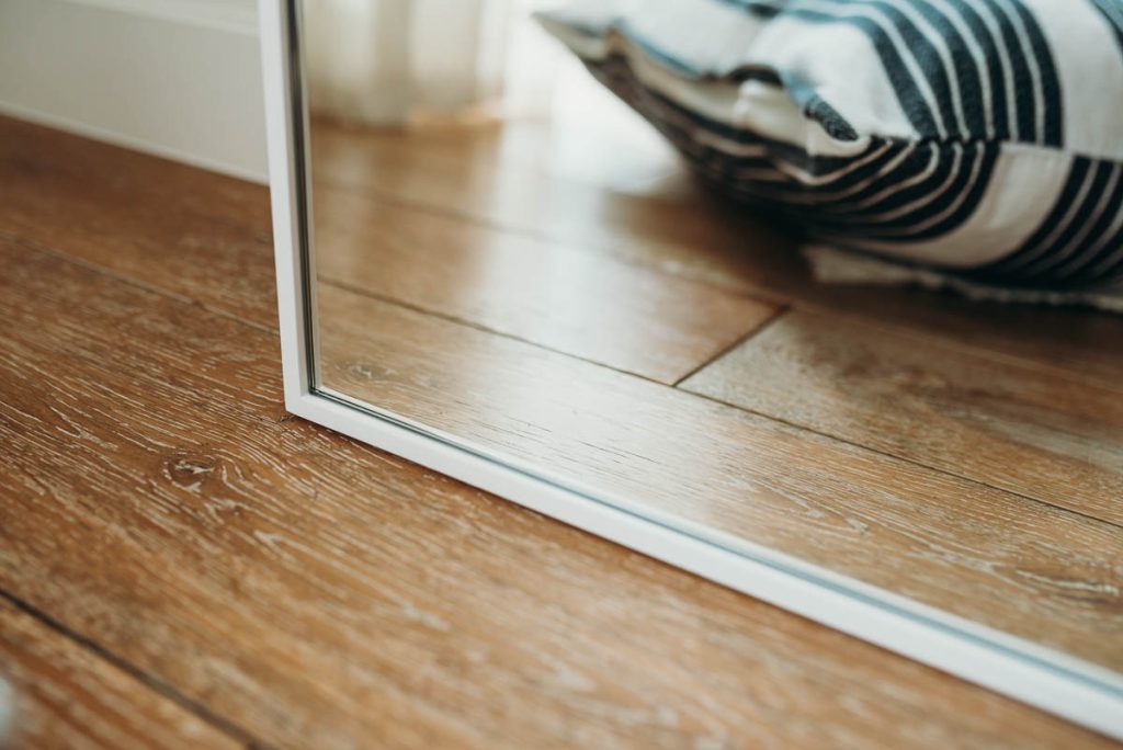 Zbliżenie na lewy róg lustra w białej ramie