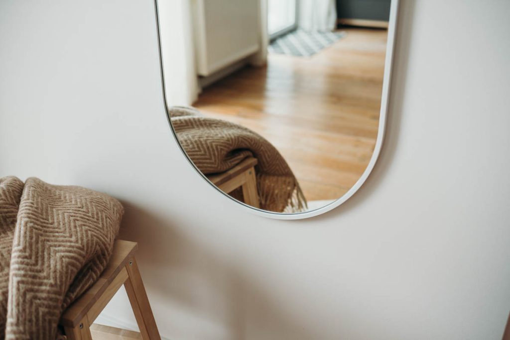 dolna cześć lustra owalnego w białej ramie na korytarzu