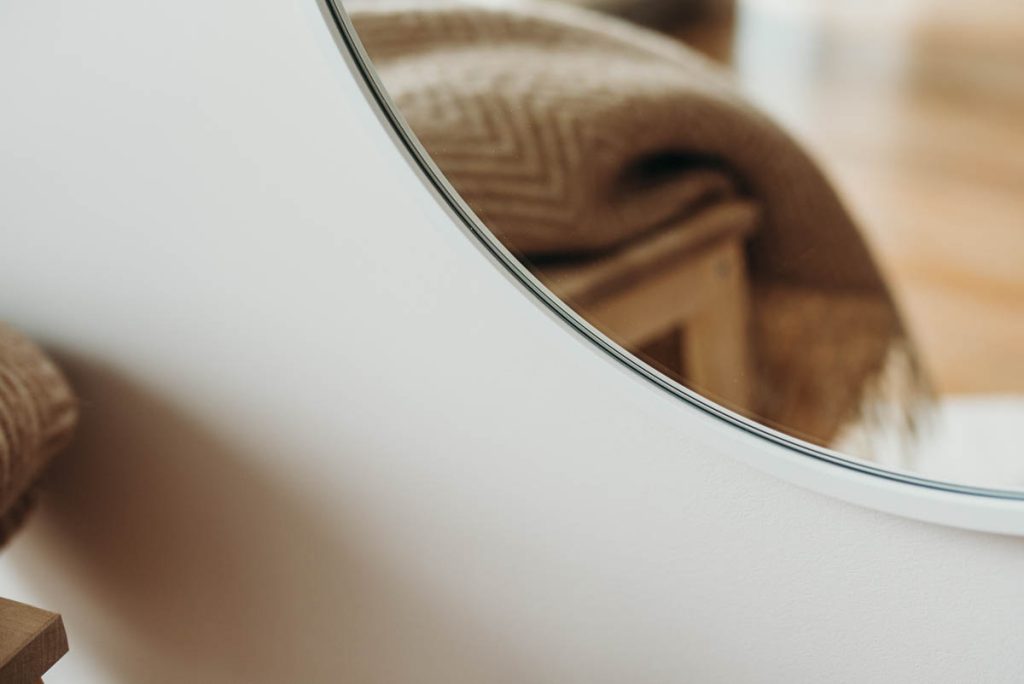 Zbliżenie na lustro owalne w białej ramie w przedpokoju