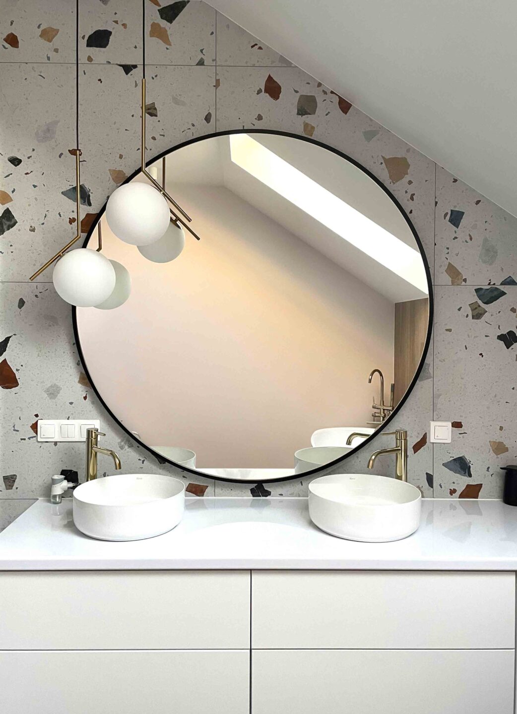 duże okrągłe lustro w łazience nad umywalką na płytkach terazzo