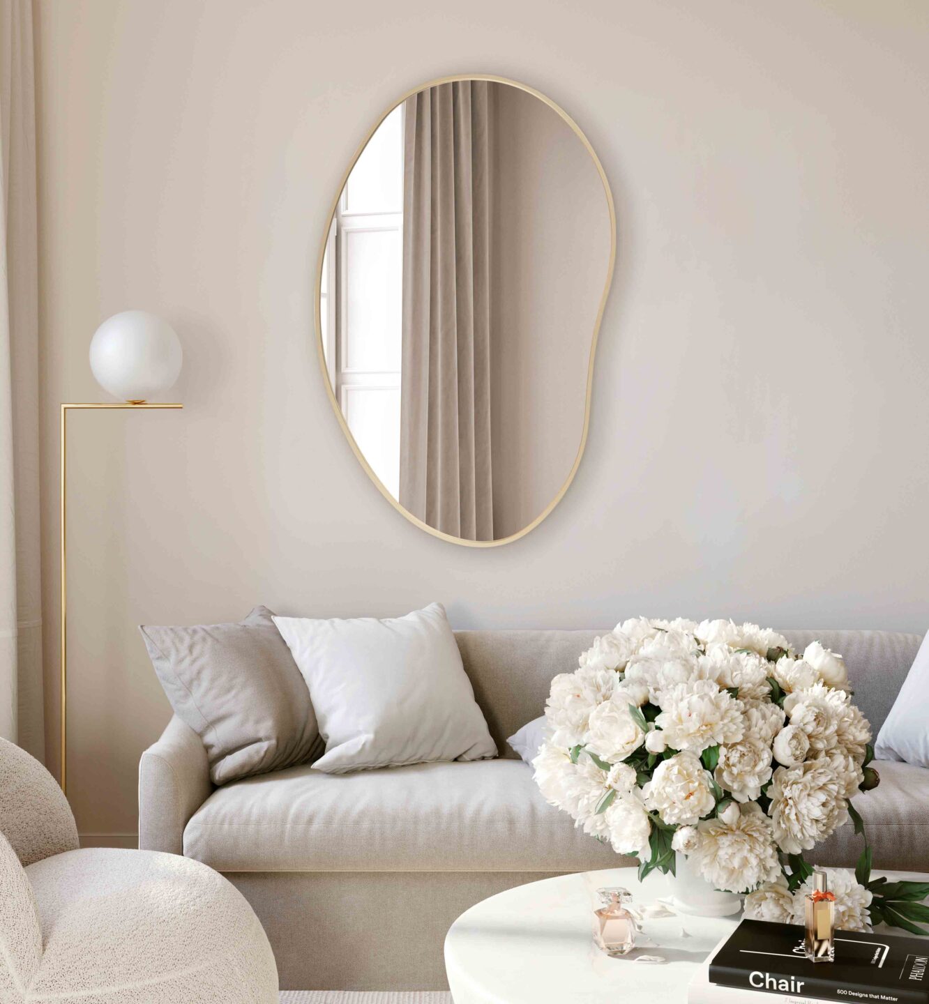 lustro organiczne w zlotej ramie w bezowym salonie nad jasna sofa