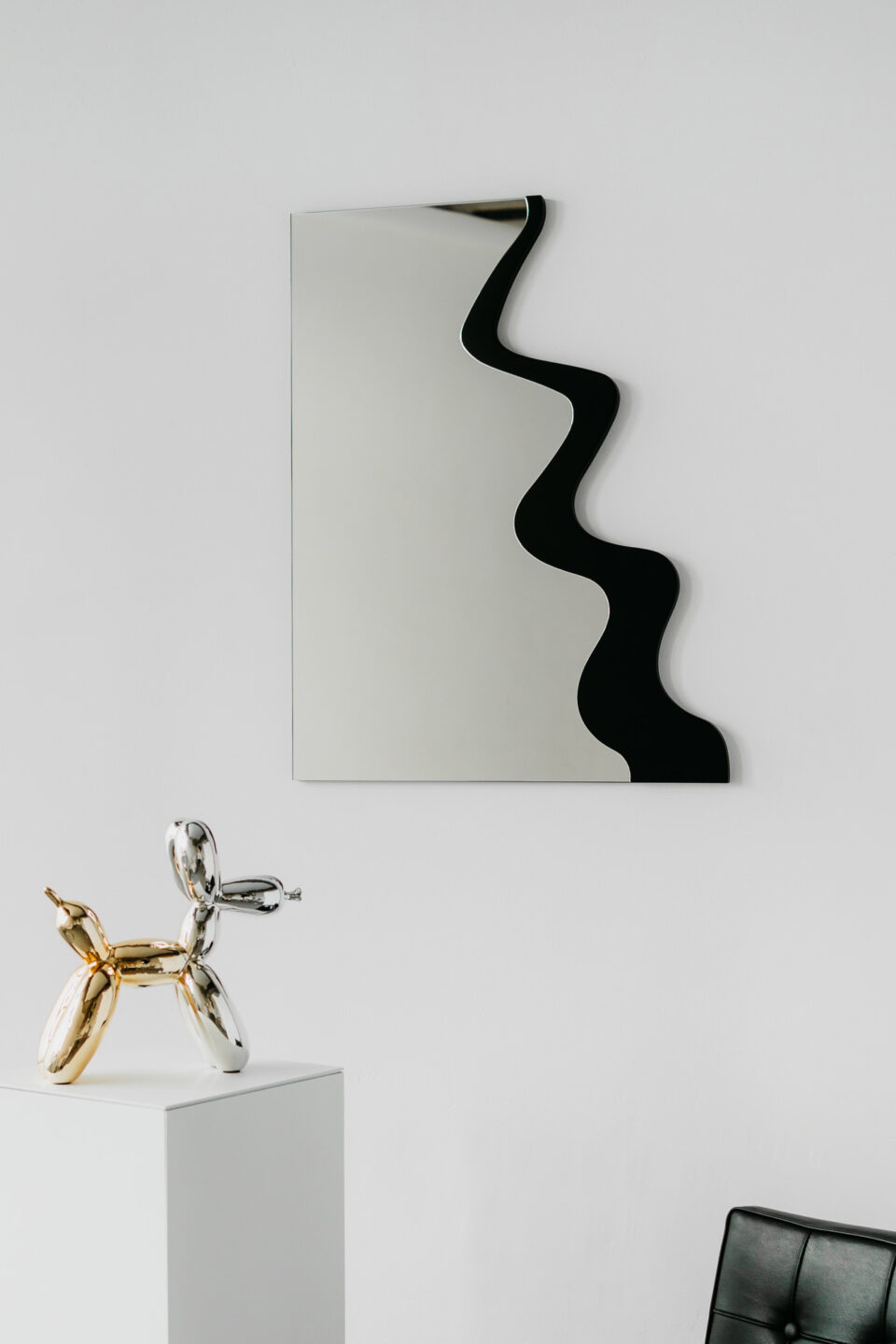 lustro w ksztalcie litery b w czarnej ramie na bialej scianie