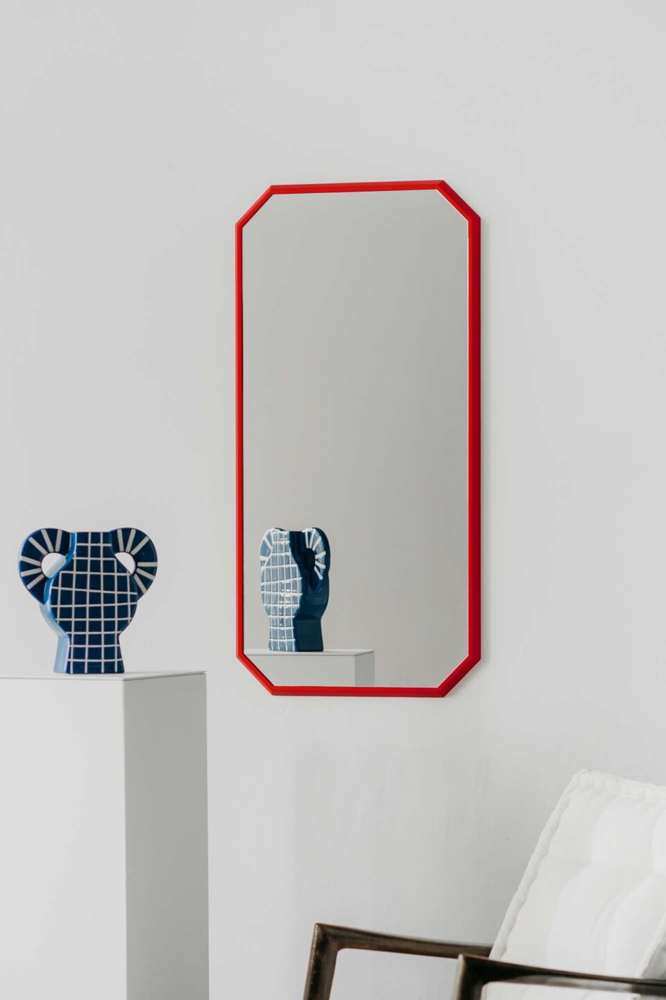 lustro w ksztalcie diamentu diamond red w czeerwonej waskiej ramie na bialej scianie