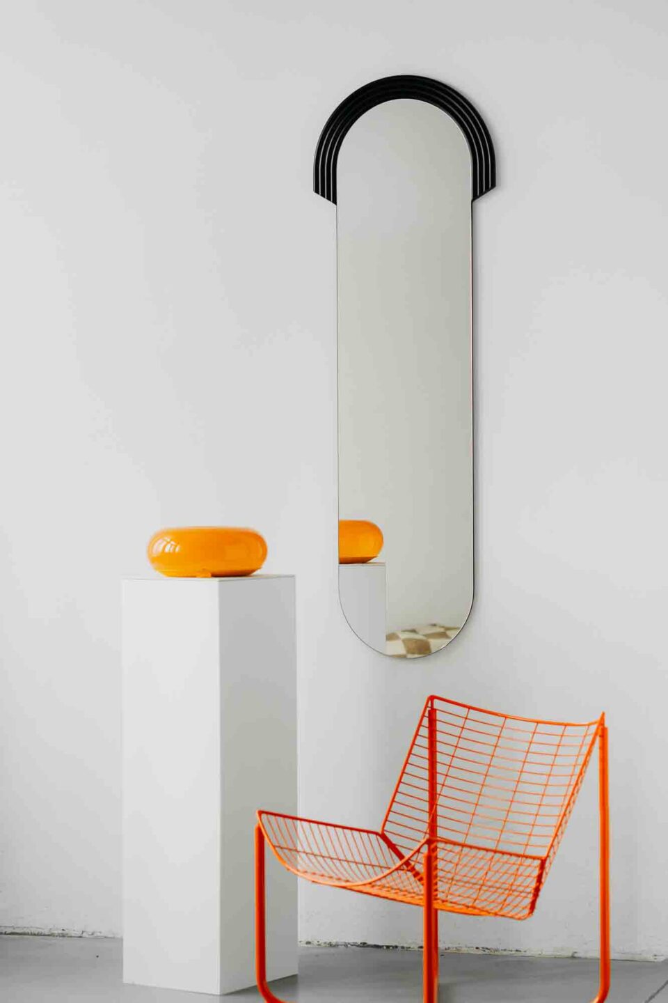 lustro owalne z czarnym ryflowanym dekorem na bialej scianie