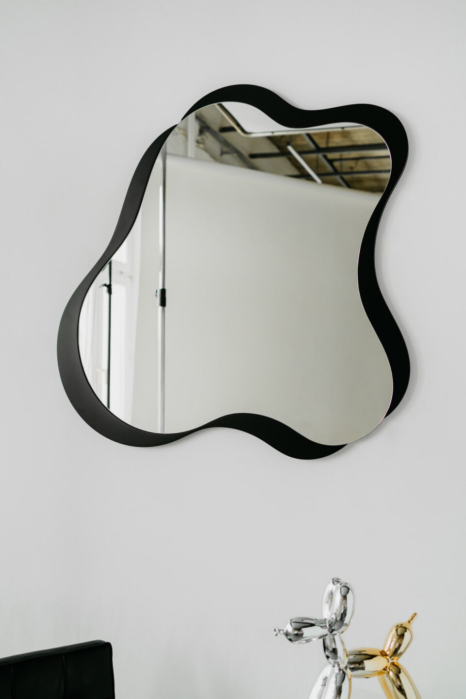 lustro organiczne marshmallow layered w czarnej nieregularnej ramie na bialej scianie
