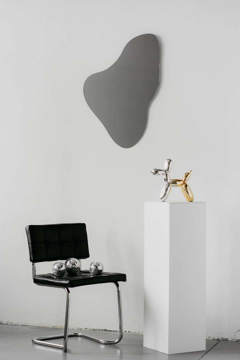 lustro twitter grey organiczne grafitowe na bialej scianie przy czarnym krzesle